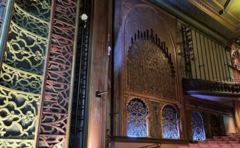 Ornate auditorium at Soho Theatre Walthamstow in London, featuring decorative walls, a balcony and rows of cinema seats.