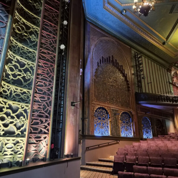 Ornate auditorium at Soho Theatre Walthamstow in London, featuring decorative walls, a balcony and rows of cinema seats.