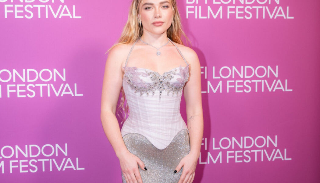 Florence Pugh at the 2026 BFI London Film Festival in a silver gown against a pink backdrop.